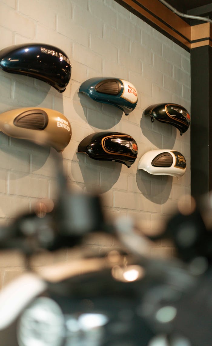 Colorful motorcycle gasoline tanks elegantly displayed on a wall indoors.