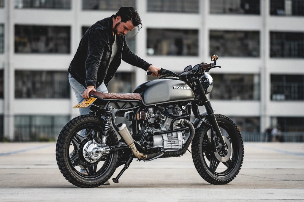 Man standing next to a custom Honda cafe racer motorcycle in Eindhoven.